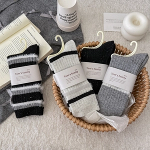 Four pairs of thick wool blend striped socks in a cozy wicker basket home setting
