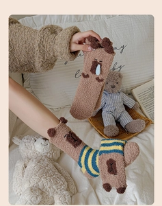 Close-up of cozy coral fleece socks with cute cartoon bear ears and striped details