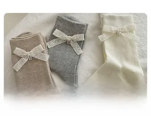 Détail de chaussettes en coton avec nœuds en dentelle blanche et breloques en métal
