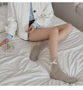 Détail du tricot de chaussettes mi-mollet avec nœud en dentelle blanche et coton peigné