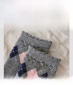 Gros plan de chaussettes en laine à losanges gris avec poignets ondulés élastiques