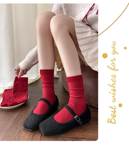 Close-up of red mid-calf socks with 3D floral relief pattern worn with Mary Jane shoes