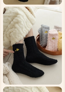 Close-up of thick coral fleece socks with sweet heart embroidery in soft home setting