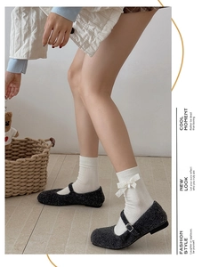Détail de chaussette en coton blanc ornée d'un nœud en dentelle et d'un pendentif