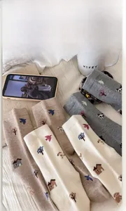 Detail of wool-blend thermal socks with cartoon dog and house knit patterns on white bedding