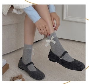 Détail de chaussettes grises avec nœud en dentelle blanche et chaussures Mary Jane en peluche