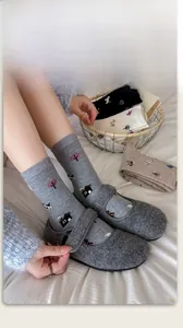 Close-up of cozy grey patterned socks with house motifs and matching wool slippers