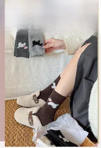 Détail de chaussettes en laine avec jacquard de chien mignon et nœud rouge en marron