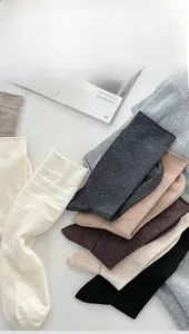 Dettaglio di calze in maglia di lana a coste in toni neutri su rivista lifestyle