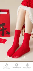 Detail of red festive crew socks with ribbed knit texture and holiday gift packaging
