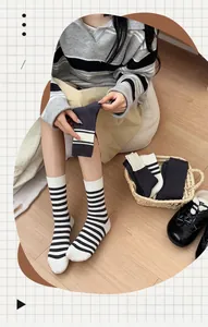Detail of striped cotton crew socks shown with model wearing black shoes and a woven basket