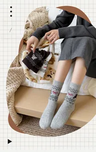 Detail von Wollsocken mit Fair-Isle-Bärenmuster und roter Schleife in Graustrick