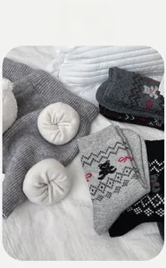 Detail von grauen Wollsocken mit süßen Bärenmustern und roten Schleifen auf weißem Stoff