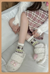 Detail of warm wool bear socks with cute heart slippers in a cozy home setting