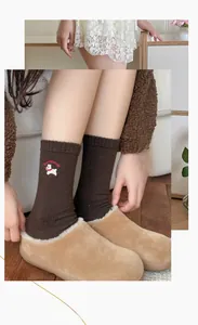 Detail of dark brown wool socks with dog embroidery and plush beige home slippers