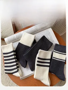 Detailed knit texture of five pairs of black and white striped cotton crew socks on magazines