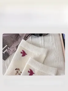 Detail of high-elasticity ribbed cuff on beige wool socks with bird pattern