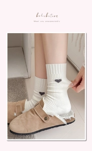 Detail of cream ribbed mid-calf socks with heart embroidery and plush home slippers