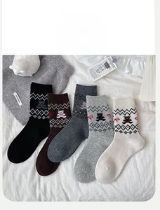 Detail der Bärenstickerei und geometrischen Strickmuster auf fünf bunten Wollsocken