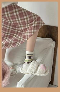 Detail of warm wool Fair Isle bear socks and white plush slippers for winter wear