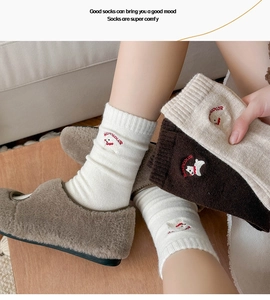 Detail of wool socks featuring cute kitten embroidery and ribbed cuffs in soft warm tones