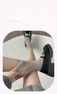 Close-up of thick beige wool socks with black polka dots showing soft elastic cuff detail