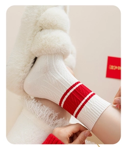 Close-up of white knitted mid-calf socks with red stripes and plush slippers