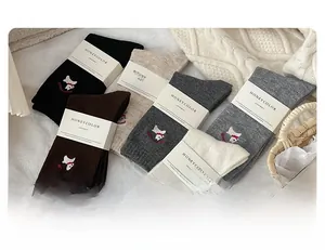 Detail of wool socks featuring cute dog embroidery and ribbed cuffs in assorted colors