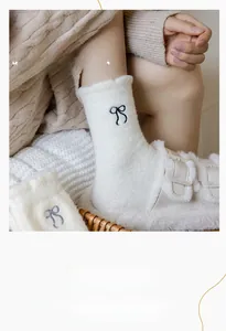 Close-up of white thermal socks with elegant black bow embroidery and plush texture