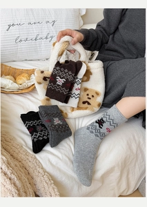 Nahaufnahme dicker Wollsocken mit süßen Bärenmustern und geometrischen Strickmustern