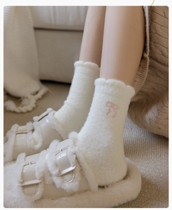 Close-up of white plush mid-calf socks featuring delicate pink embroidered bow details