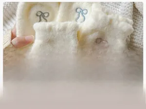 Macro detail of soft cream fleece fabric with delicate blue and pink bow embroidery