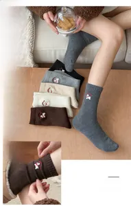 Close-up of cute dog embroidery on rib knit wool socks in neutral earth tones