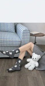 Detail of grey knitted mid-calf socks featuring white sheep pattern and soft texture