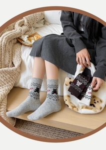 Detail von Wollsocken mit Bärenmuster und geometrischen Winterwald-Motiven
