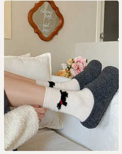 Détail de chaussettes en laine crème avec motif chien et chaussures en feutre gris