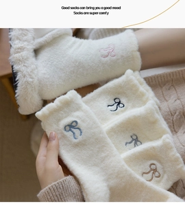 Detail of warm white plush socks featuring delicate bow embroidery and ruffled edges