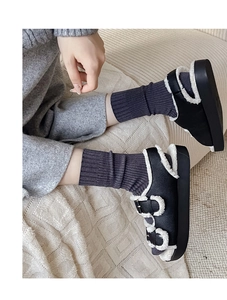 Detail of warm black faux leather slippers with white sheepskin lining and metal buckles