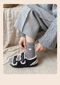 Detail of white heart pattern on gray ribbed socks worn with fur-lined buckle sandals