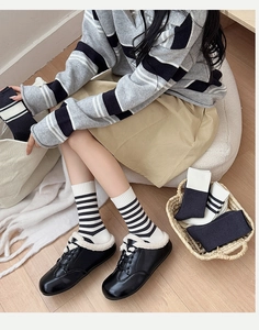 Detail of striped cotton knit socks showing black and white striped patterns on a model