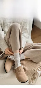 Detail shot of khaki suede mules with plush faux fur lining and knit socks for winter cozy style
