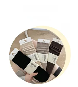 Detail of wool crew socks in black beige and brown shades with minimalist packaging