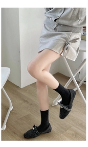 Close-up of black ribbed wool socks paired with tweed pearl bow flats and a grey skirt
