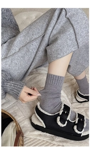 Close-up of gray ribbed cashmere-like socks worn with plush-lined buckled sandals