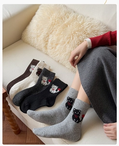 Detailaufnahme der dicken Wollsocken mit eingestrickten Katzenmotiven und roter Schleife
