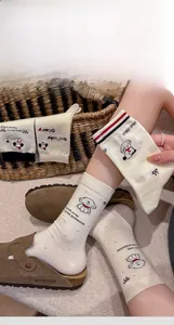 Detail of cream cotton socks featuring cartoon dog patterns and handmade stitching