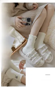 Close-up of white plush thermal socks featuring delicate bow embroidery and lace trim