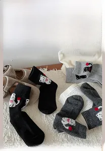 Detail der süßen Cartoon-Katzenstickerei auf schwarzen und grauen Wollsocken