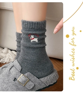 Detail of dark grey wool socks featuring a cute white dog embroidery and red lettering