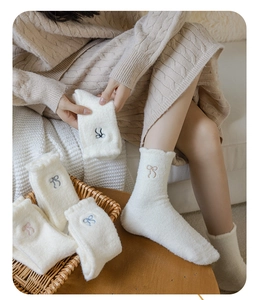 Detailed view of plush coral fleece socks with delicate embroidered bow accent and soft texture